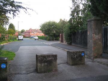 View of road with concrete blocks across and pillar to one side