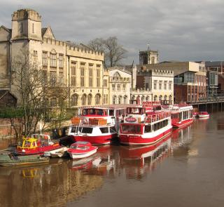 Red boats, wide flooded river, riverside buildings