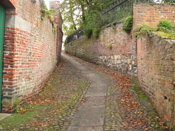 Alley between brick and stone walls, crooked, ancient, cobbled