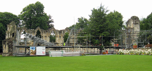 Medieval abbey ruins with seating for plays constructed in front, tree in middle of seating
