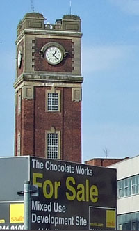 Factory tower with clock, For Sale boards in foreground