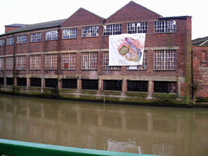 Some rather ugly, but functional buildings, draped with a banner advertising how someone thinks they could improve the area and give it a silly new name.