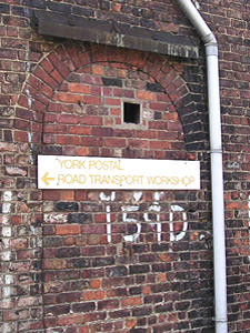 Much-altered wall, showing former doorway/window, with sign