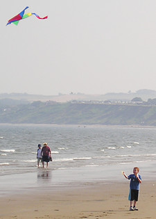 Young boy flying multi-coloured kite on Filey beach